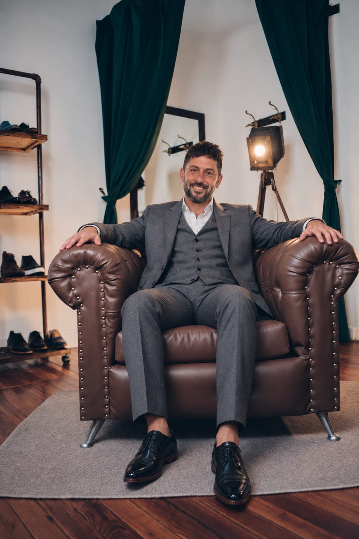 Nicolas Calo en el sillón del atelier, de traje gris con chaleco