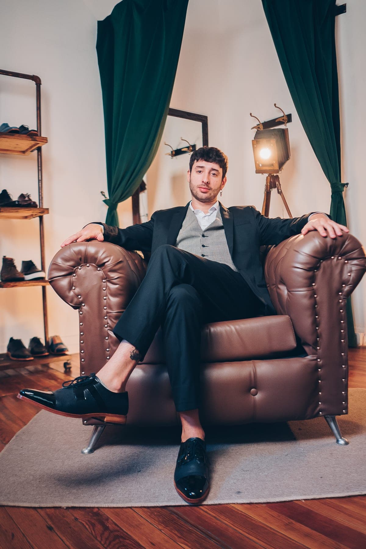 Agustin Palermo en el sillón del atelier, de traje negro con chaleco a cuadros