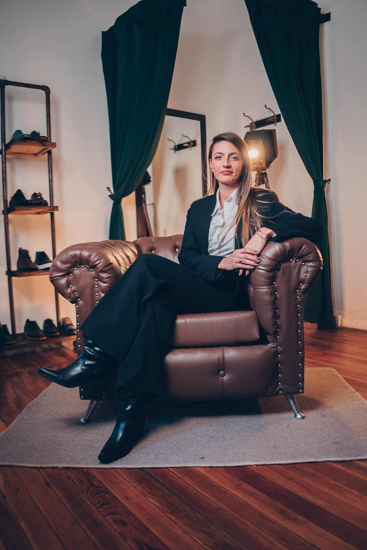 Florencia Palermo en el sillón del atelier, de traje negro y camisa blanca