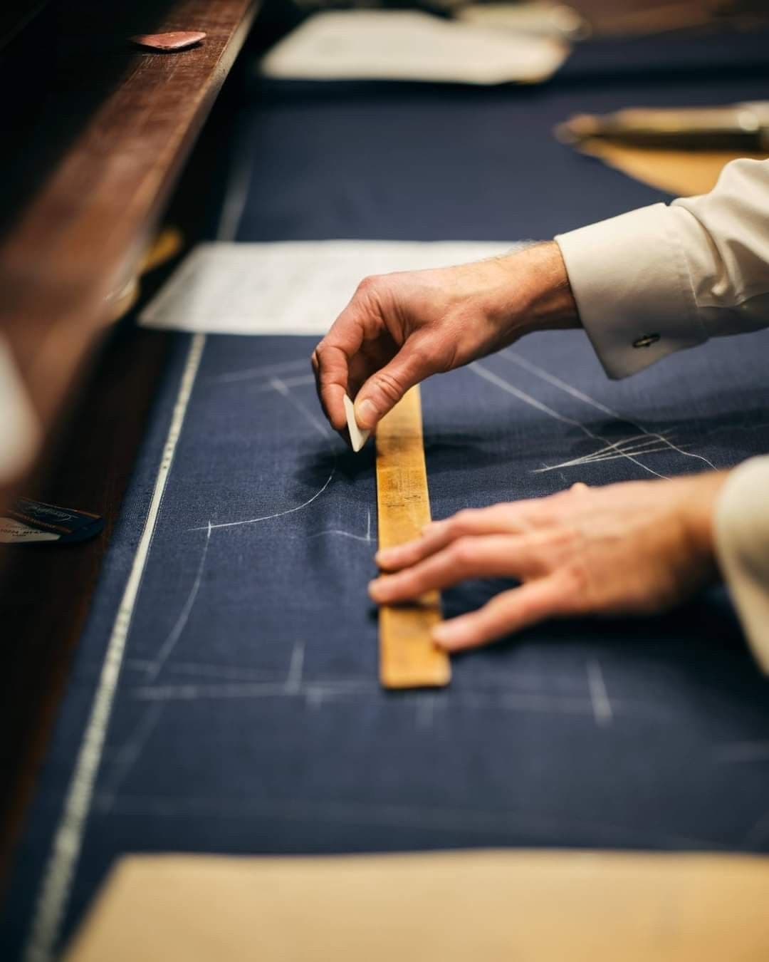 Manos midiendo un paño azul con regla de sastre