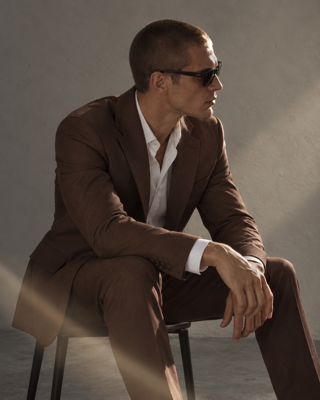Modelo sentado con el ambo chocolate, de perfil